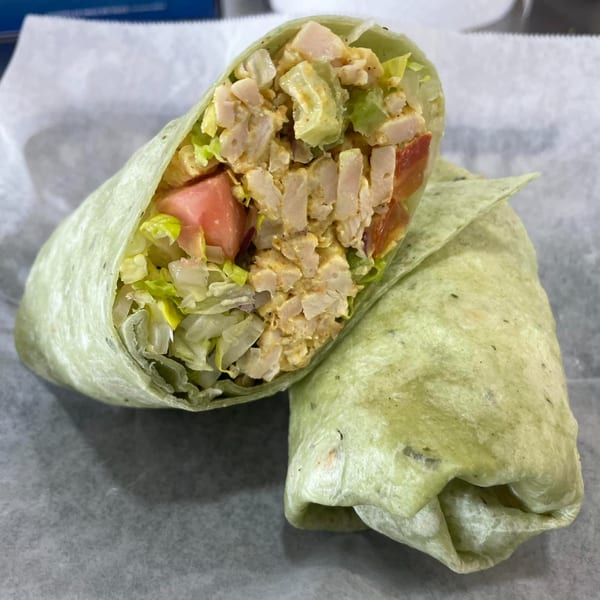 Bigfoot Subs chicken salad wrap, cut in half, showcasing chicken, lettuce, and tomato.