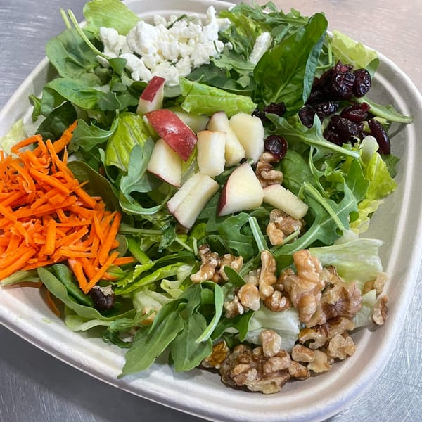 A Bigfoot Subs salad with mixed greens, shredded carrots, feta, cranberries, apples, and walnuts.