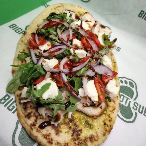 Naan bread topped with chicken, arugula, mozzarella, tomatoes, red onion, and balsamic glaze.